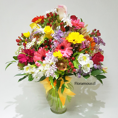 Florero de vidrio con gran variedad de flores de temporada combinación multicolor